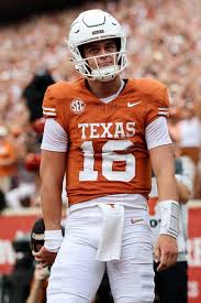 Texas Longhorns coach Steve Sarkisian talks strategy with quarterback Arch Manning during a college football game, focusing on player development and team leadership.